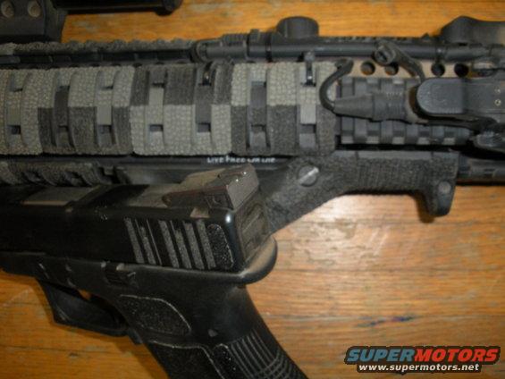 close-up of assault rifle with pistol attached, rifle has camo paracord wrap