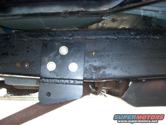 Close-up of a vehicle's frame with a newly welded bracket and three bolts