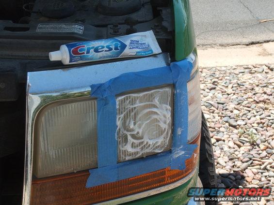Headlight being cleaned with Crest toothpaste and blue tape