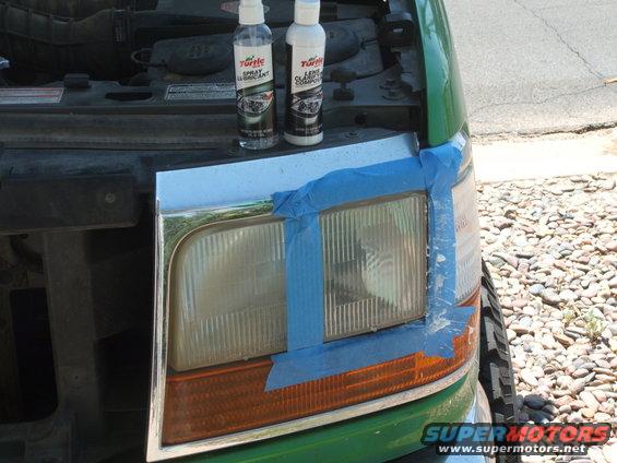 Green Ford Bronco with taped headlight assembly and two Turtle Wax bottles on the hood