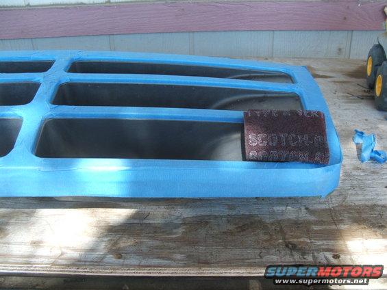 Taped off grille with Scotch-Brite pad on wooden surface