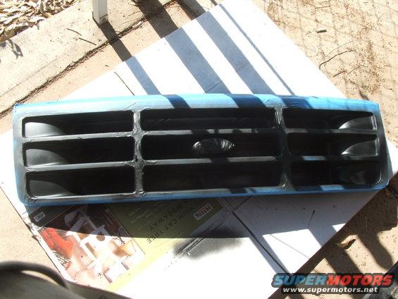Ford Bronco grille taped off for painting. Oval Ford logo visible in center