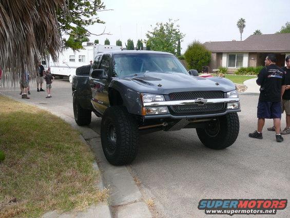 Dark gray pickup truck with off-road modifications, lifted suspension, and large tires
