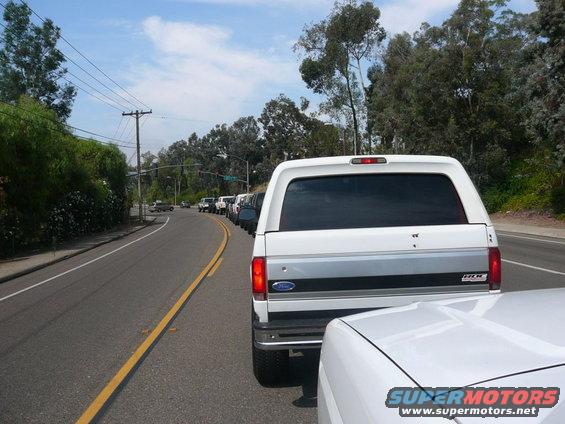 Rear view of a white 1988 Ford Bronco with a camper shell in traffic