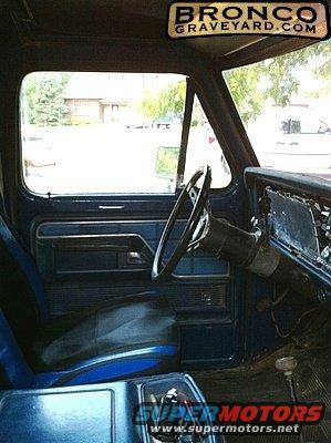 1978 Ford Bronco interior showing driver's seat, door panel, and dashboard. Bronco Graveyard.com sticker visible