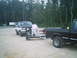 1988 Ford Bronco - A person attends to a trailer connected to a two-tone SUV, with a black pickup truck nearby.
