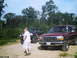 1988 Ford Bronco - A man stands near two Ford Broncos on a dirt path with trees in the background.