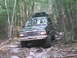 1988 Ford Bronco - SUV navigates a challenging rocky path through a dense forest.