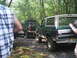 1988 Ford Bronco - A green Ford Bronco with a white top is parked on a dirt path, with another SUV behind it in a wooded area.
