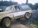1988 Ford Bronco - Mud-covered 1988 Ford Bronco ascends a ramp during an off-road event.