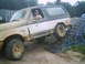 1988 Ford Bronco - This Ford Bronco is climbing a ramp, covered in mud. The driver is visible behind the wheel.