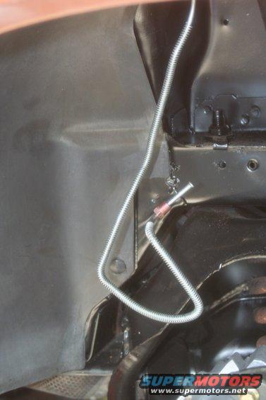 Close-up of a metal brake line running along the underside of a vehicle, near suspension parts