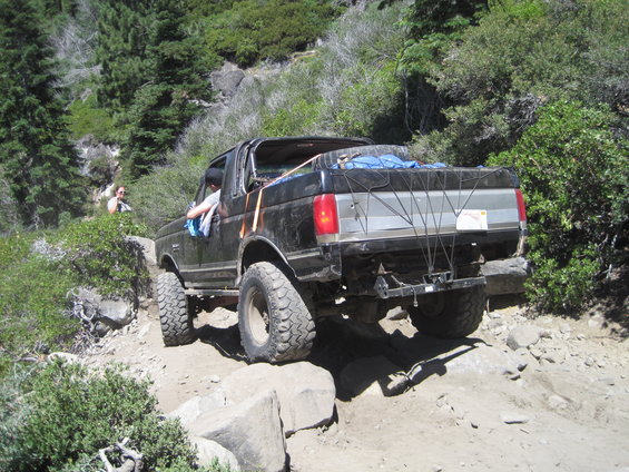 1989 Ford Bronco off-roading on a dirt path with large rocks