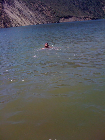 Person swimming in a lake with hills in the background