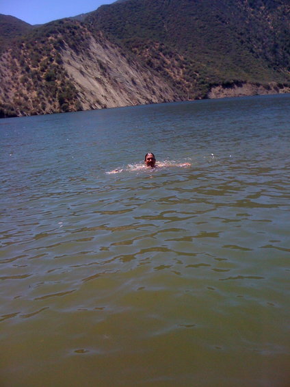 Person swimming in a lake with a mountain in the background