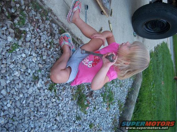 Kid with wrench near a tire and some tools on the ground