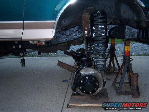 Teal and tan 1996 Ford Bronco front suspension on jack stands, undergoing repairs