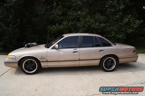 Side view of a tan 1993 Ford Crown Victoria with a large hood scoop and black rims