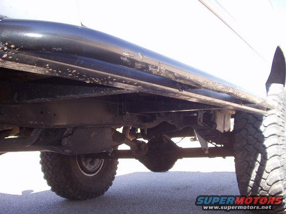 Side view of truck undercarriage, showing frame, suspension, and tires