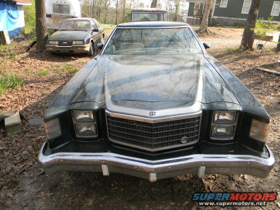 Front view of a dark colored Ford Ranchero GT with a chrome grille and GT badging. Another car is parked behind it