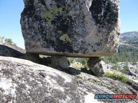 Large boulder balanced on smaller rocks on a mountainside