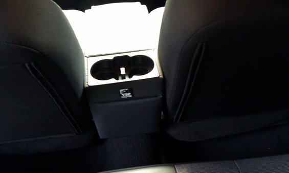 Center console with dual cup holders and a VIP logo, viewed between car seats