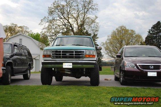 Teal Ford Bronco with lifted suspension and aftermarket wheels, viewed from the front