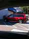 2007 Subaru Impreza - A red minivan with a roof box is parked in a lot outside a building.