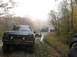 1986 Ford Bronco - A convoy of SUVs navigates a challenging muddy path through an autumn forest.