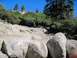 1986 Ford Bronco - A dark SUV tackles a challenging rocky terrain on a sunny day.
