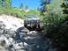 1986 Ford Bronco - This 1980s Ford Bronco tackles a challenging, boulder-strewn path under a clear blue sky.