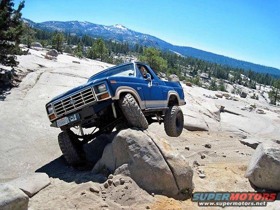 Blue Ford Bronco climbing over rocks on a trail
