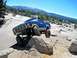 1986 Ford Bronco - This modified Ford Bronco is navigating a rocky off-road course with a clear blue sky above.