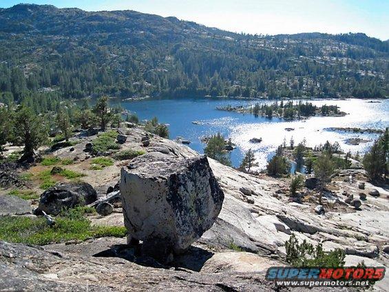 Rocky landscape with a blue lake and pine trees under a clear sky