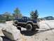 1986 Ford Bronco - This modified SUV is navigating a rocky trail with one wheel in the air.