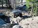 1986 Ford Bronco - This Ford Bronco navigates a rocky off-road trail, kicking up dust as it goes.