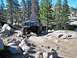 1986 Ford Bronco - This lifted 1980s Ford Bronco navigates a challenging, rocky off-road path through a forest.