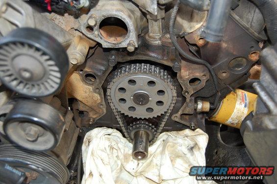 Engine timing chain and gears with oil filter. White cloth covers part of the engine block