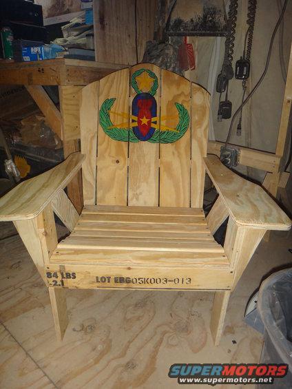 Wooden Adirondack chair with military insignia on backrest and stenciled lot number on seat base