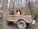 1978 Ford Bronco - Two people are in a muddy 1978 Ford Bronco, parked in a wooded area.
