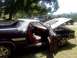 1979 Ford Ranchero - A black 1979 Ford Ranchero with its hood and driver's door open, showing its red interior, sits in a grassy area with other vehicles in the…