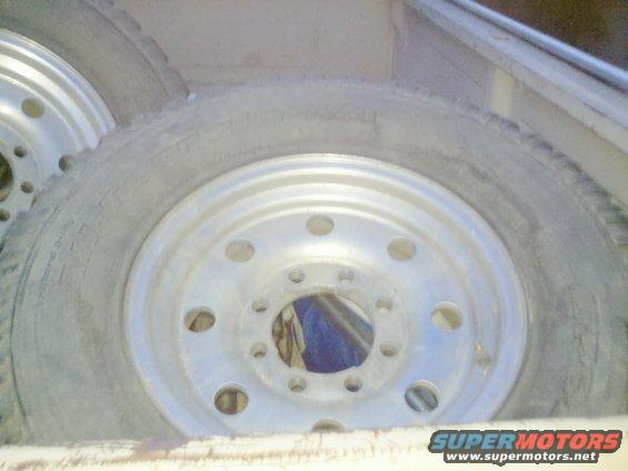 Two truck tires and aluminum wheels stacked in a cargo area. The tires are worn