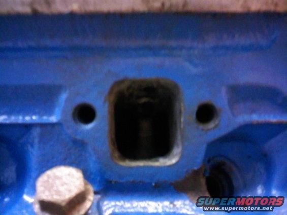 Blue painted engine block with a square intake port and two bolt holes