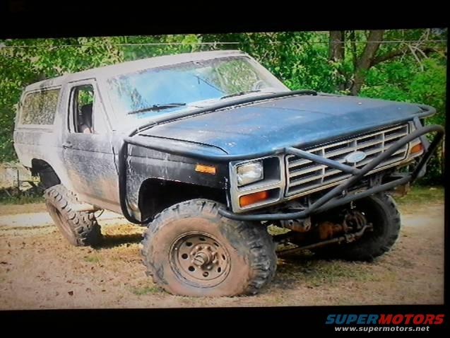 Ford Bronco with a brush guard and off-road tires, parked on dirt