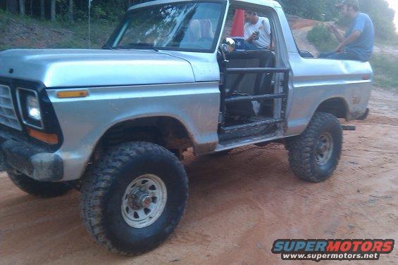 1978 Ford Bronco with roll cage, silver, off-road tires, seen from the front-left