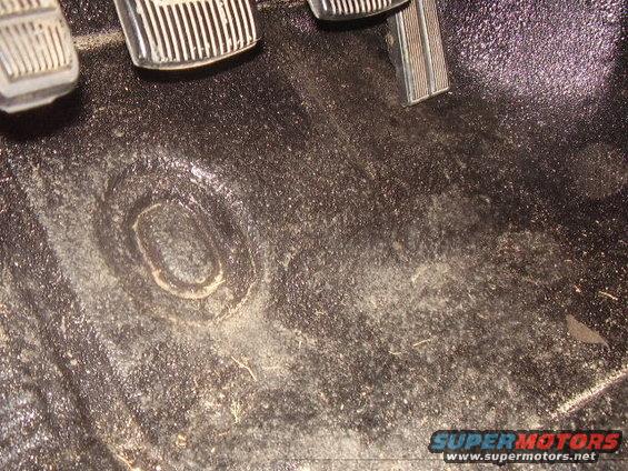 Interior floor mat with metal pedals and a circular indentation