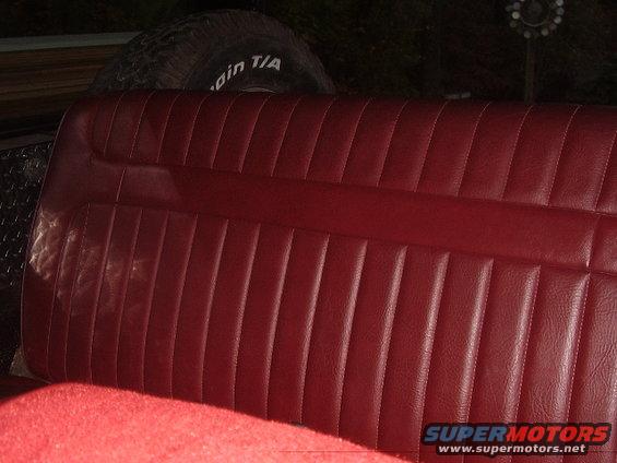 Red vinyl bench seat with a spare tire visible behind it