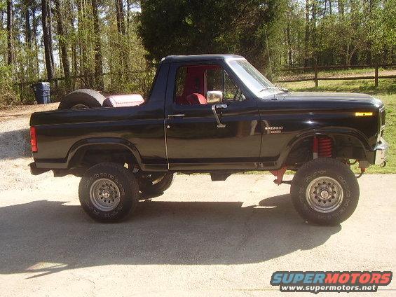 Black 1986 Ford Bronco side view with lifted suspension and red interior