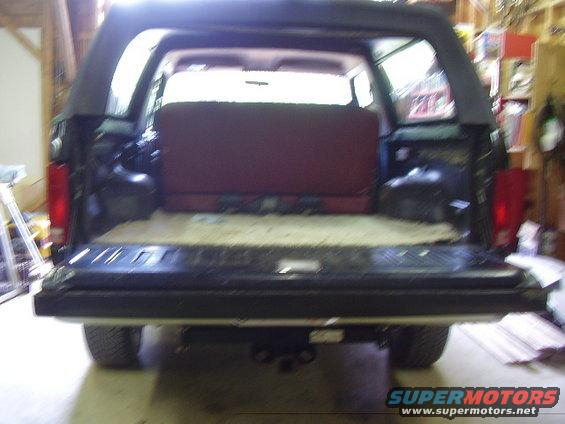 Rear view of dark SUV with tailgate open, showing red seats inside