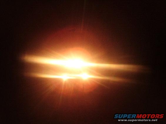 Headlights with lens flare, dark background, Supermotors.net logo
